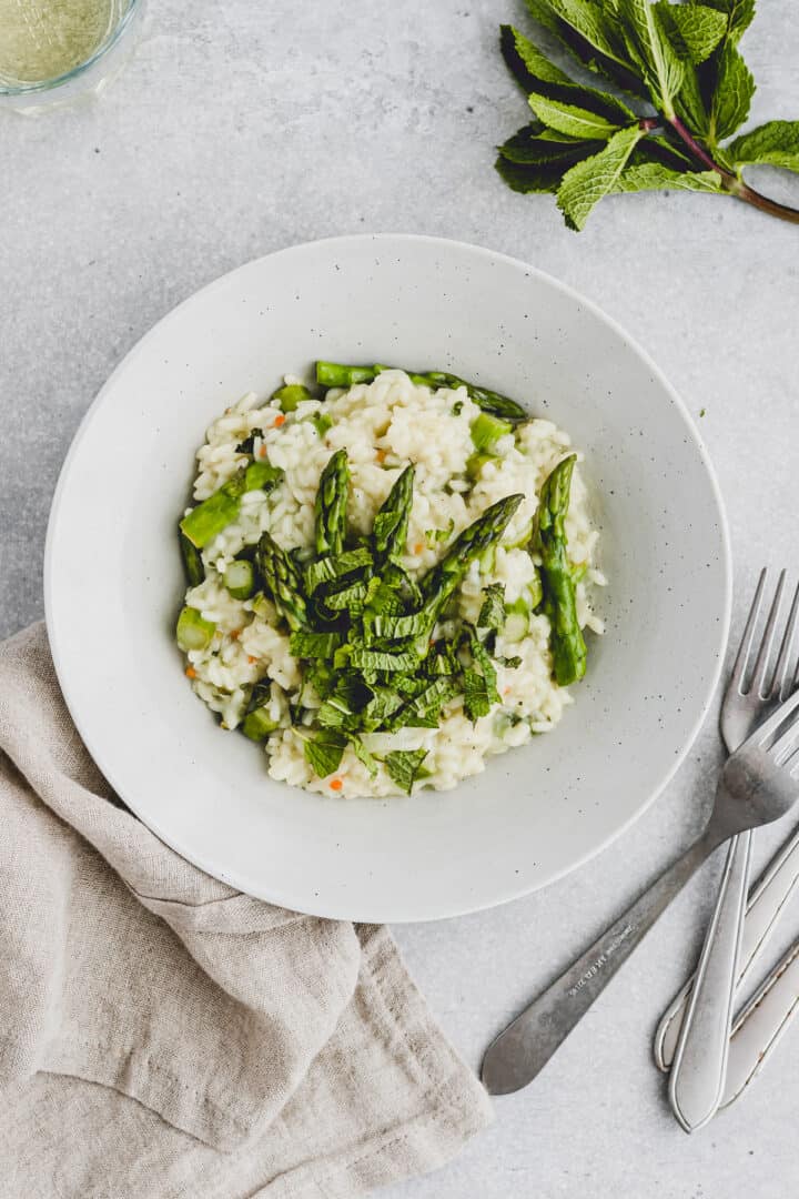 spargelrisotto mit frischer minze neben einem glas wein