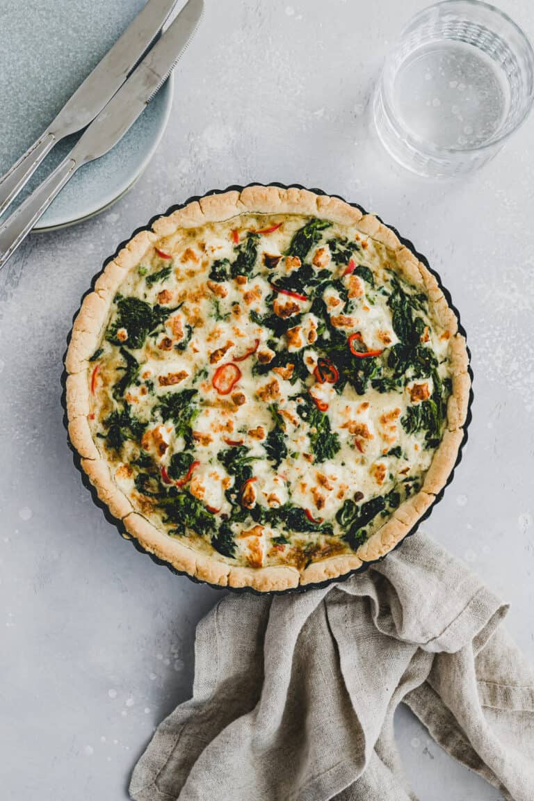 spinat feta quiche in einer quicheform neben einem glas mit wasser