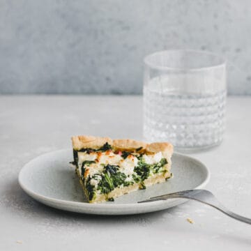 a slice of spinach and feta quiche on a blue plate