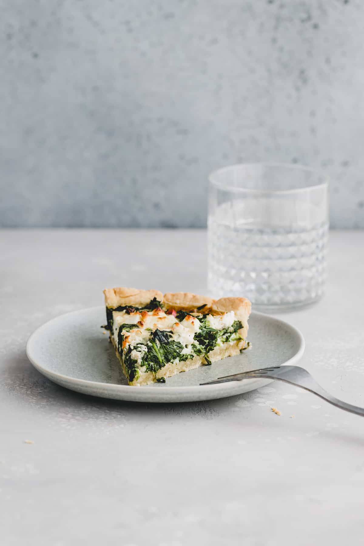 a slice of spinach and feta quiche on a blue plate