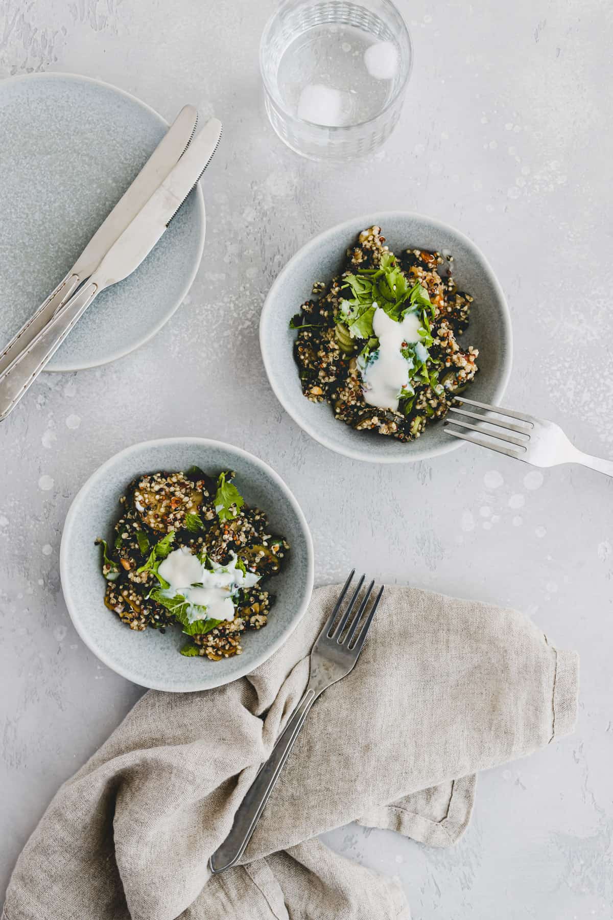 veganer quinoa salat mit joghurt und kräutern in zwei blauen schüsseln