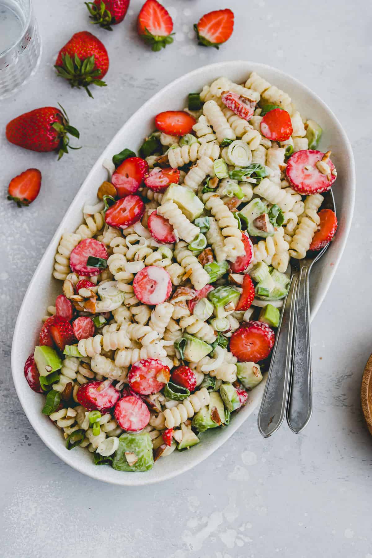 vegan cold pasta salad with strawberries and avocado on a serving platter