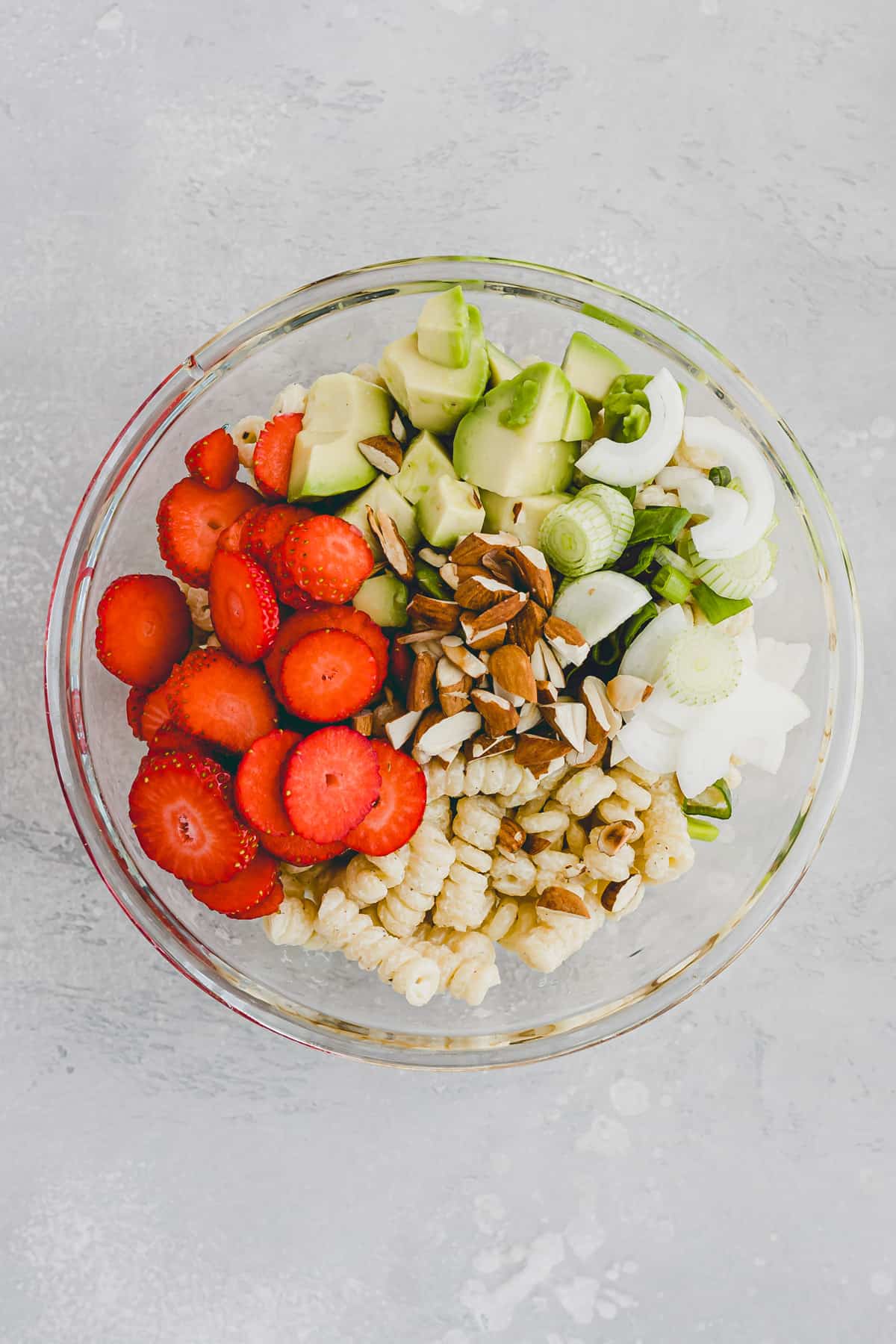 zutaten für sommerlicher nudelsalat mit erdbeeren und avocado in einer glasschüssel