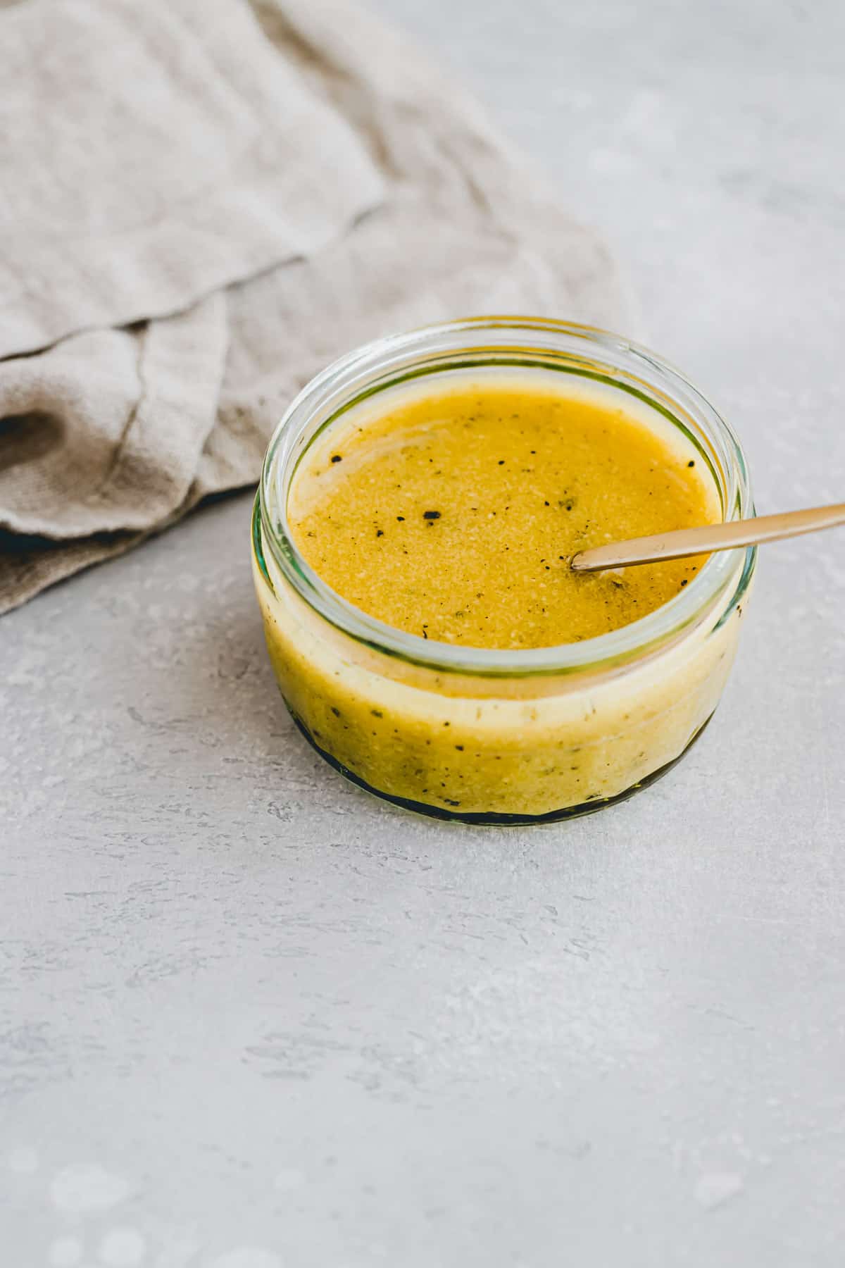 maple syrup mustard dressing in a jar with a golden spoon