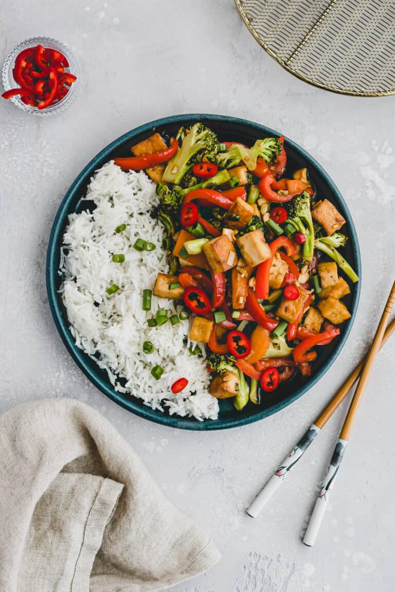 tofu stir fry on a plate next to chopsticks