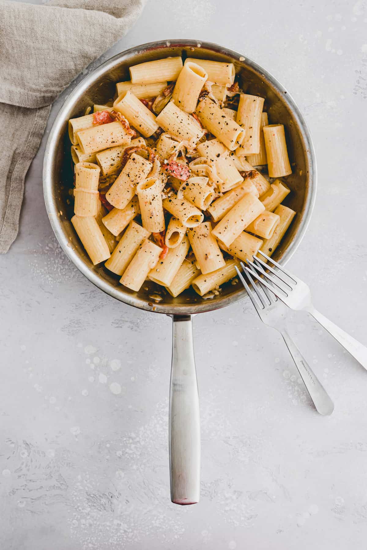 vegan sun dried tomato pasta in a skillet with two forks