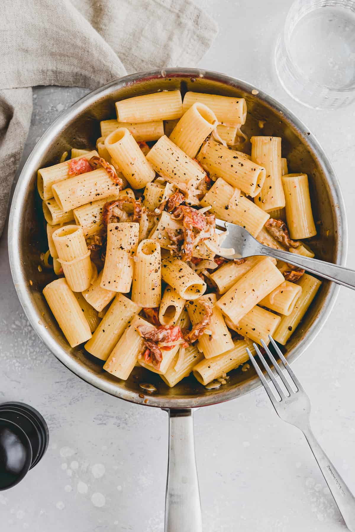 vegan pasta with sun dried tomatoes and onion in a skillet