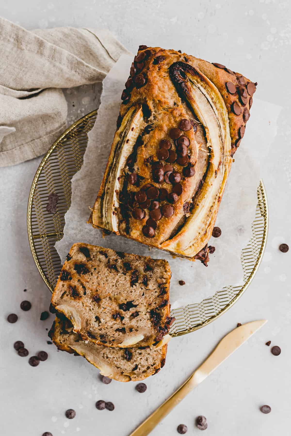 bananenbrot vegan mit schoko drops auf einem goldigen gitter