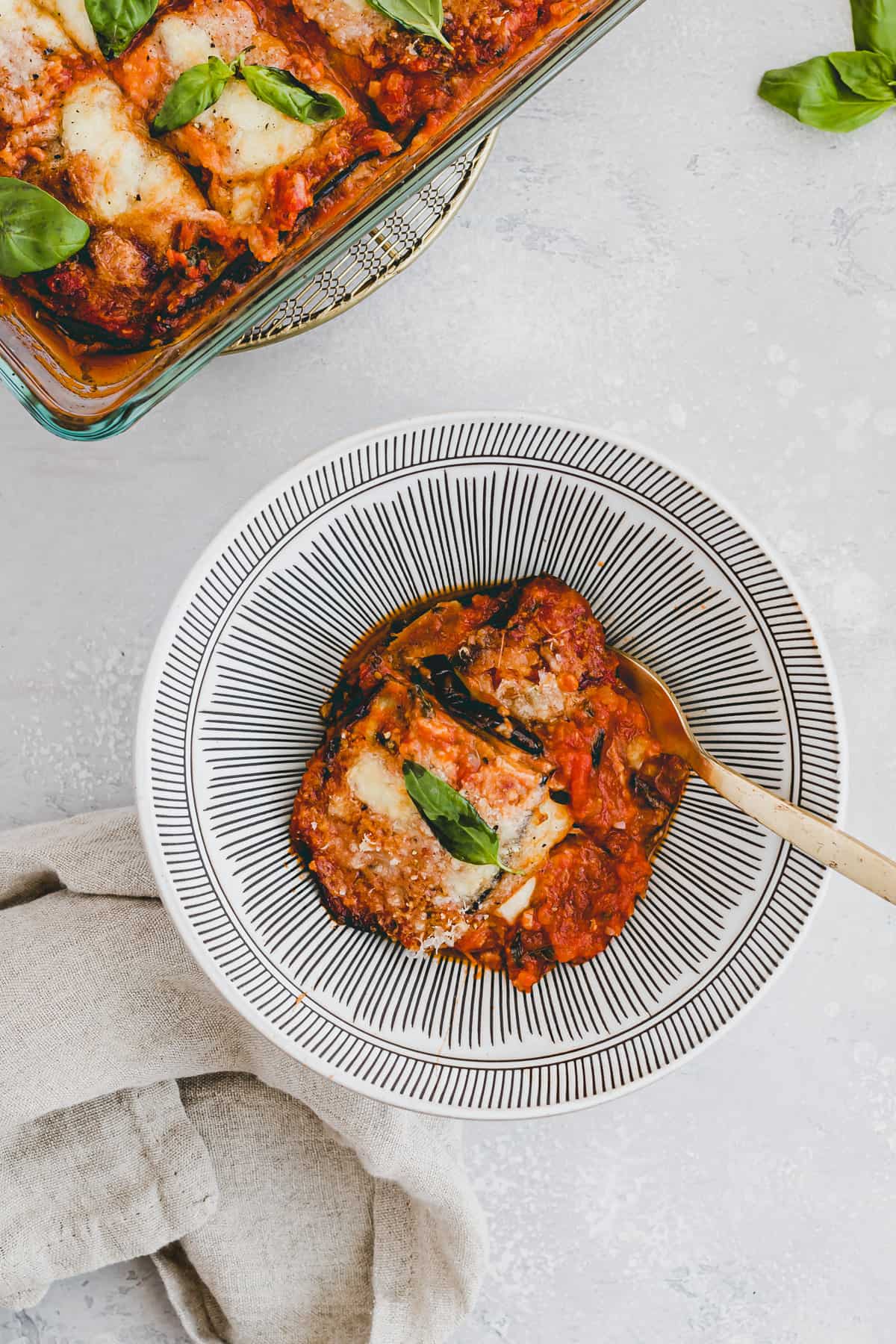 aubergine parmigiana in einer schüssel mit einer goldenen gabel