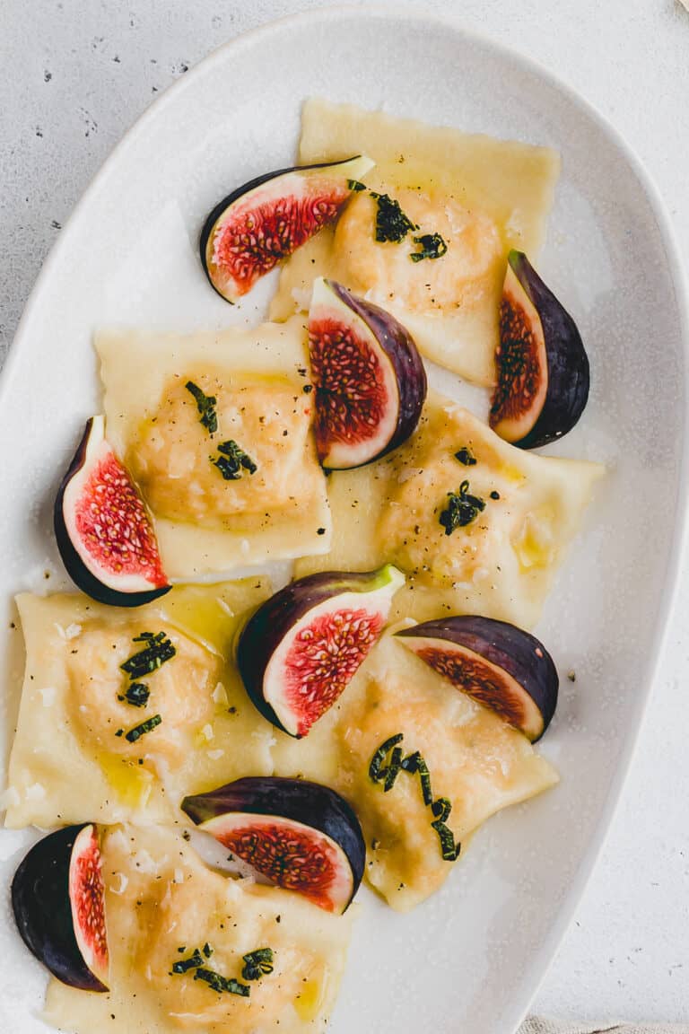 hausgemachte ravioli mit kürbis ricotta füllung auf einem teller serviert und mit feigen dekoriert