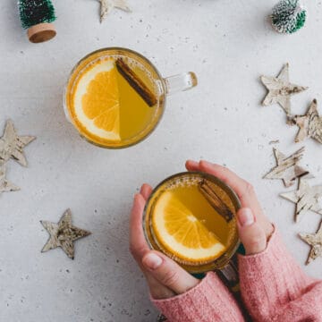 zwei hände halten ein glas weißer Glühwein