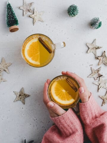 zwei hände halten ein glas weißer Glühwein