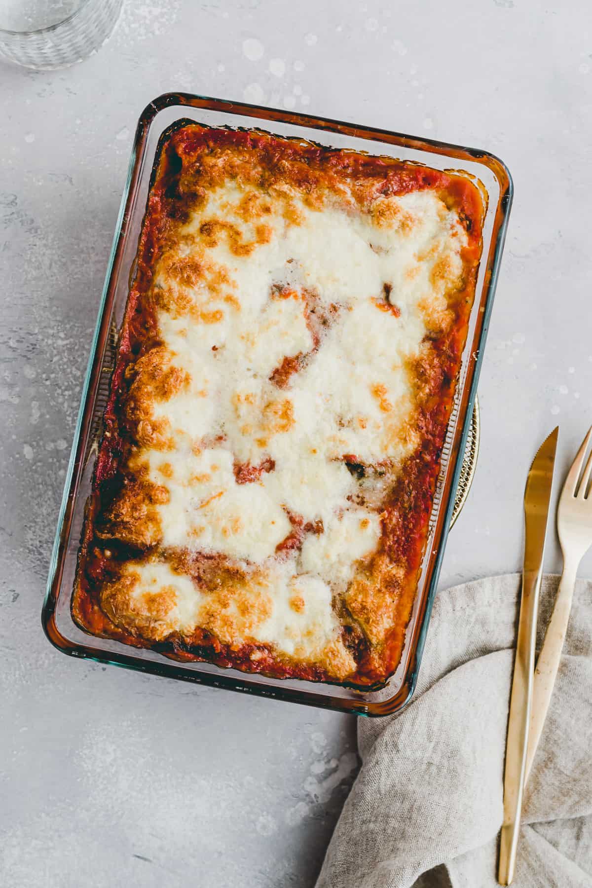 homemade spinach cannelloni topped with mozzarella in a baking dish
