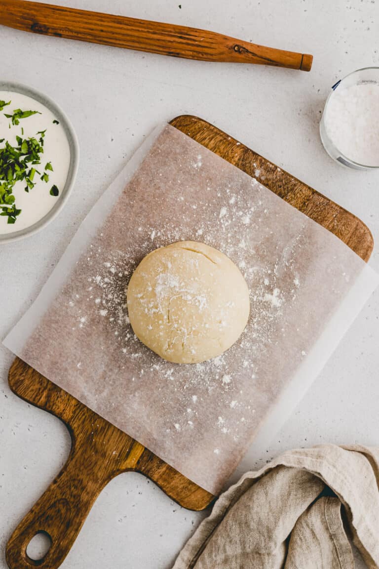 selbstgemachter flammkuchenteig auf einem holzbrett