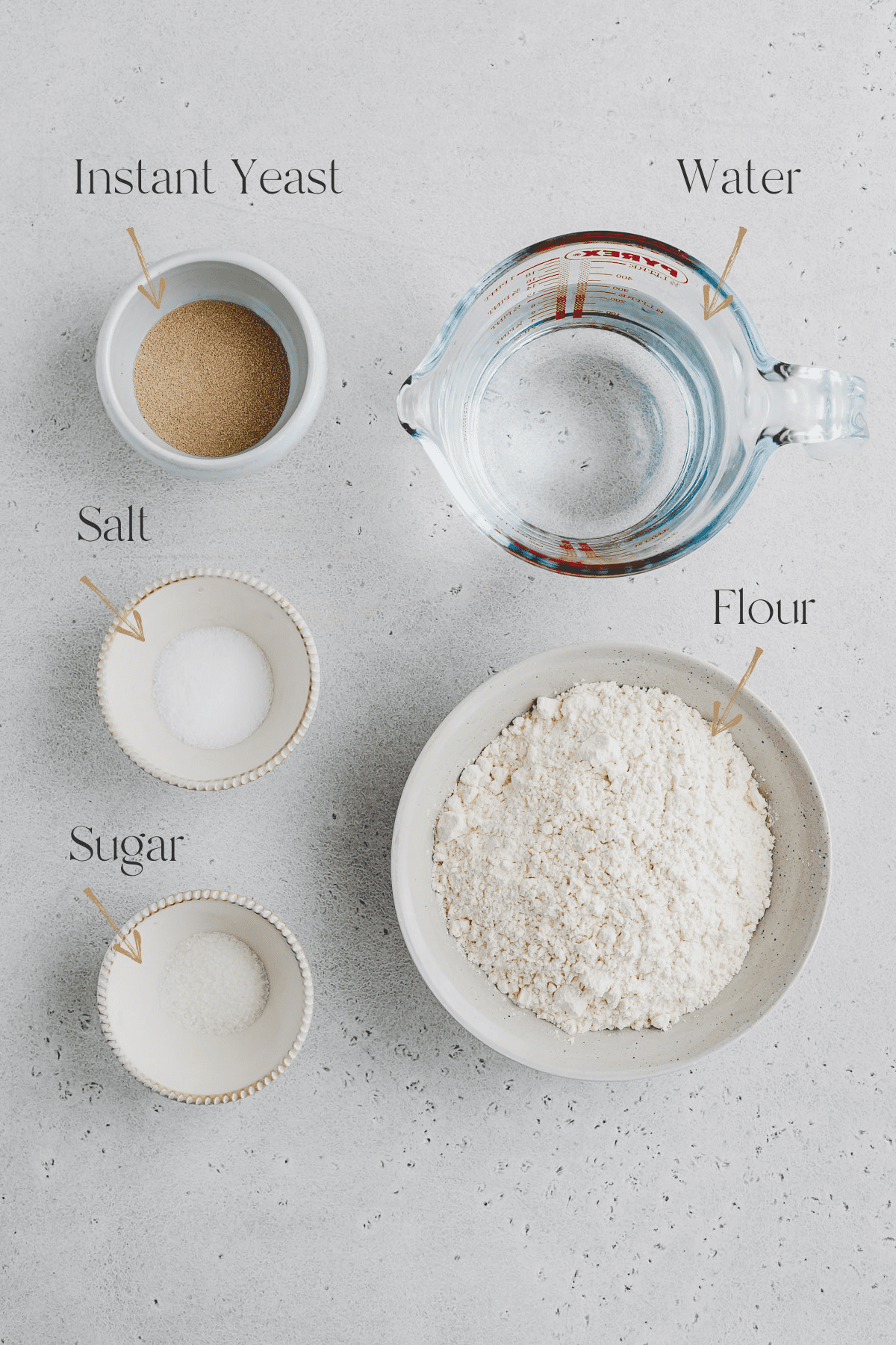Top view of Ingredients for No Knead Focaccia recipe including salt, flour, sugar, water and yeast. 