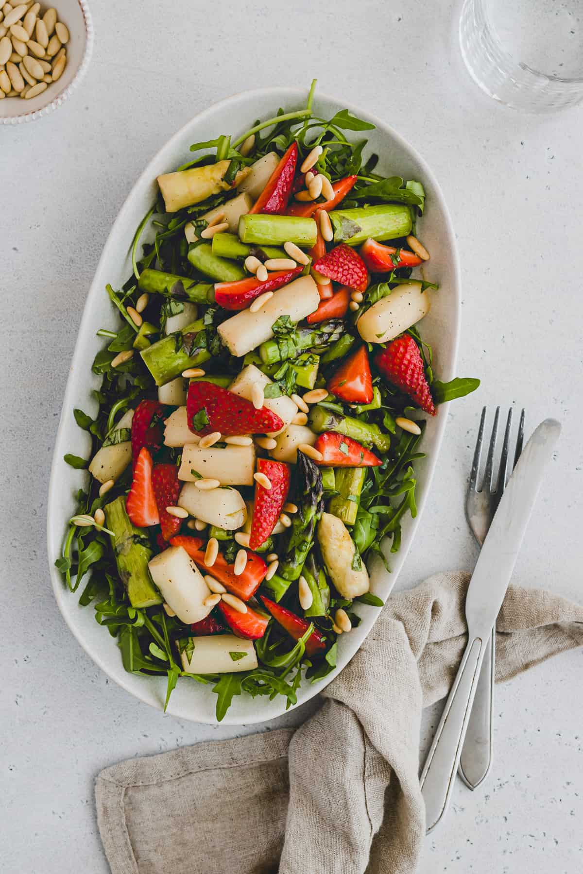 strawberry asparagus salad with rocket and pine nuts on a plate