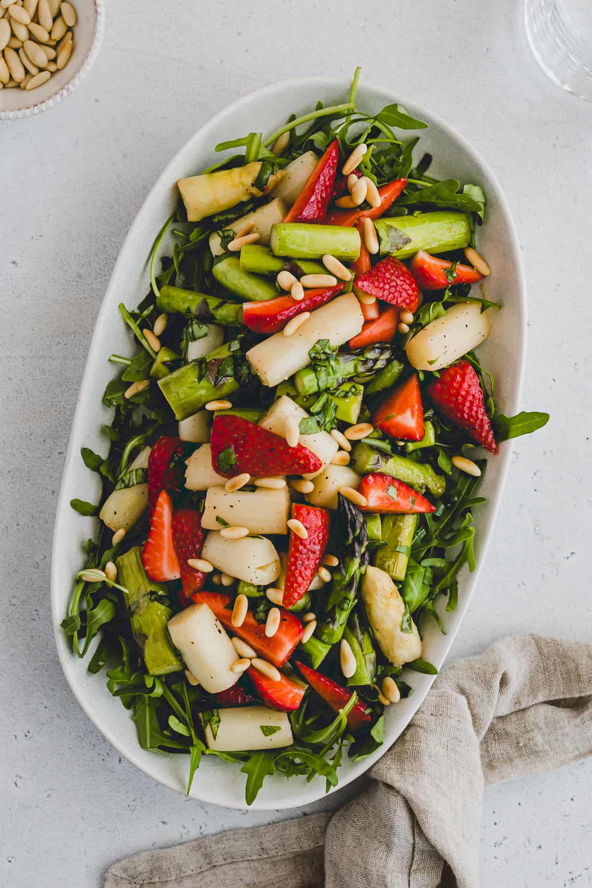 spargel erdbeer salat auf einer platte mit rucola und pinienkernen