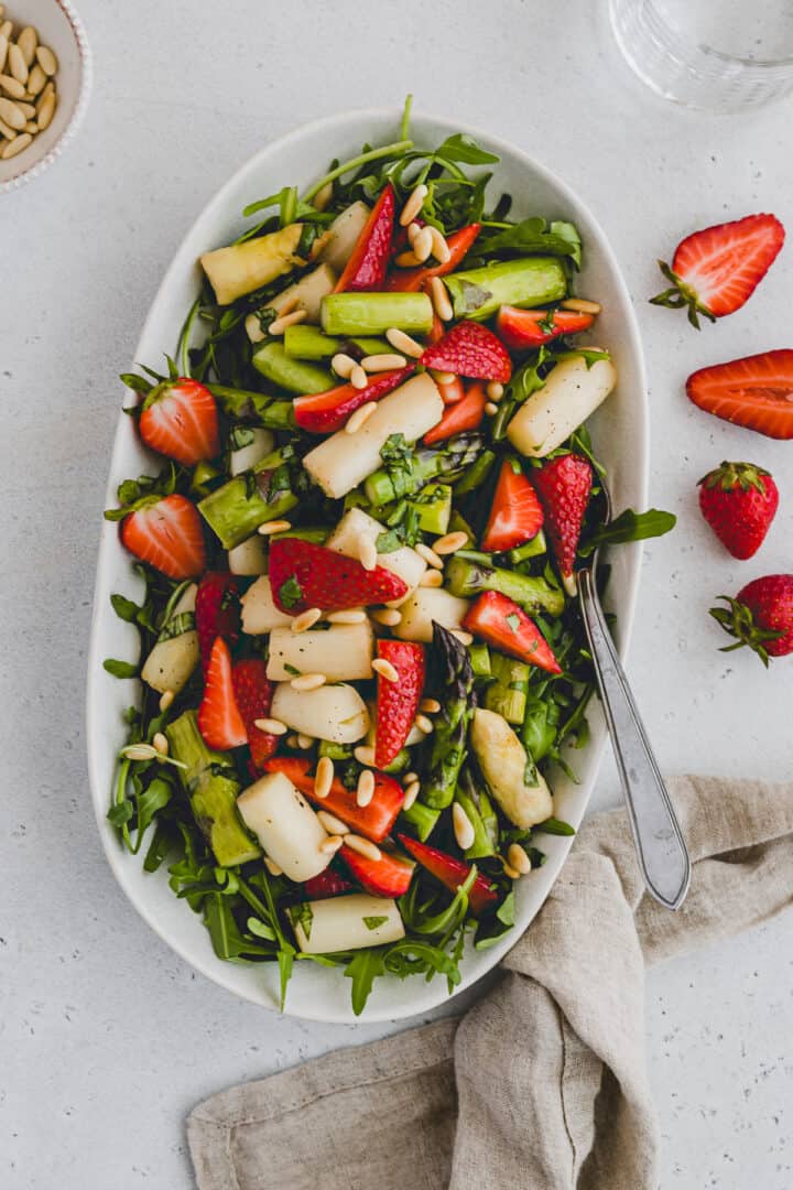 spargelsalat mit erdbeeren und rucola auf einer servierplatte