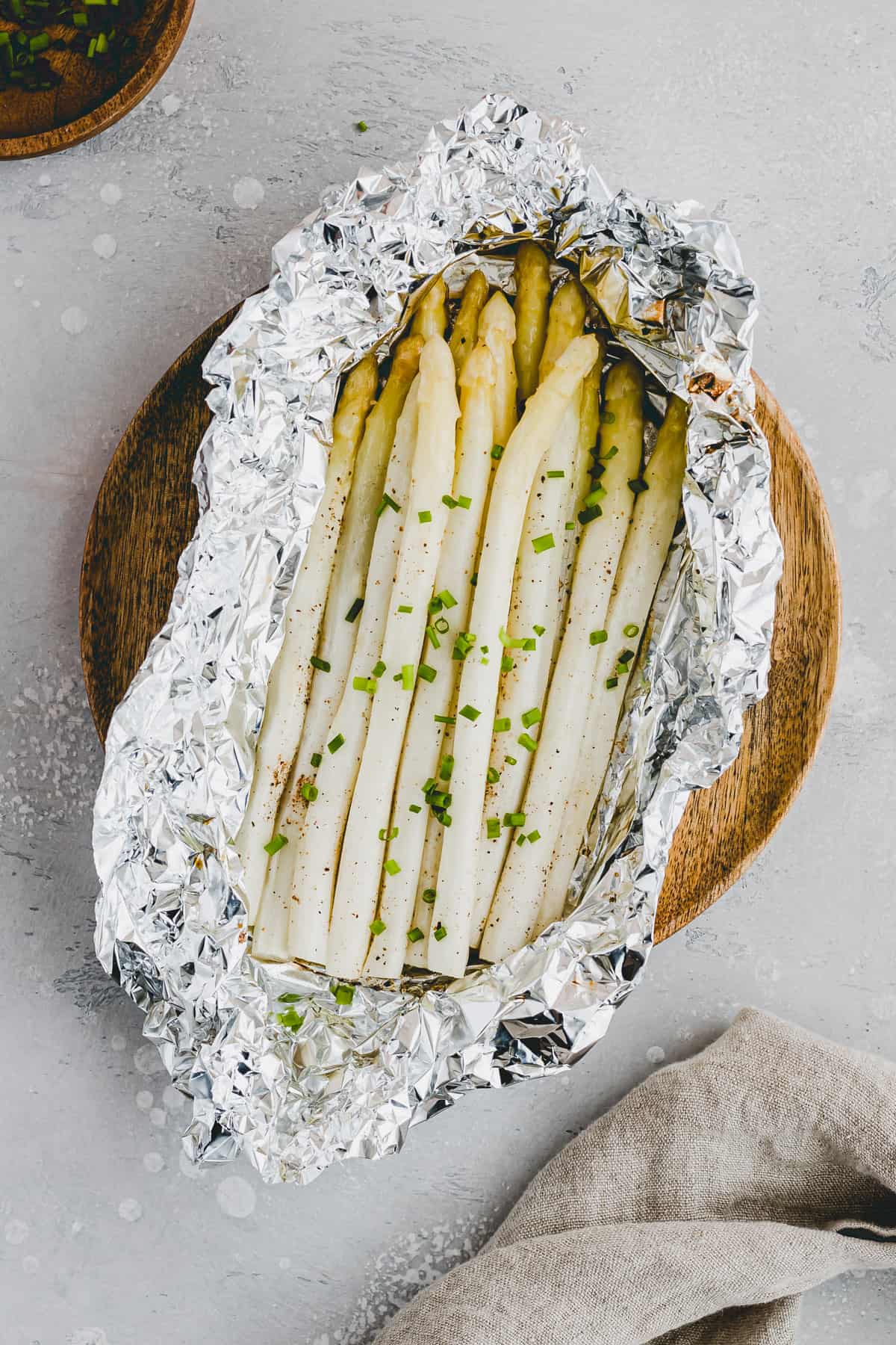 weisser spargel in alufolie mit schnittlauch dekoriert