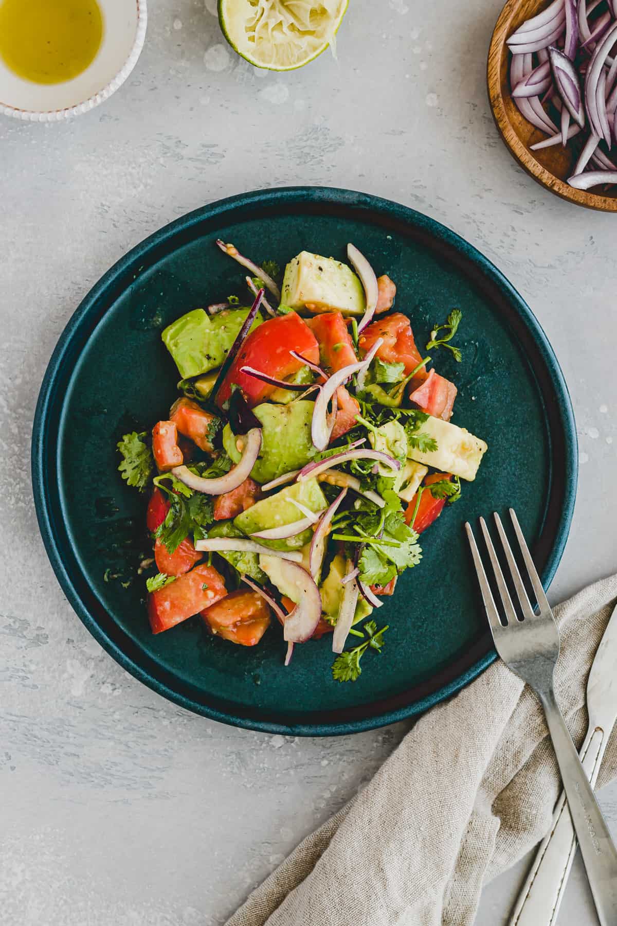 avocado and tomato salad on a blue plate with a fork and knife