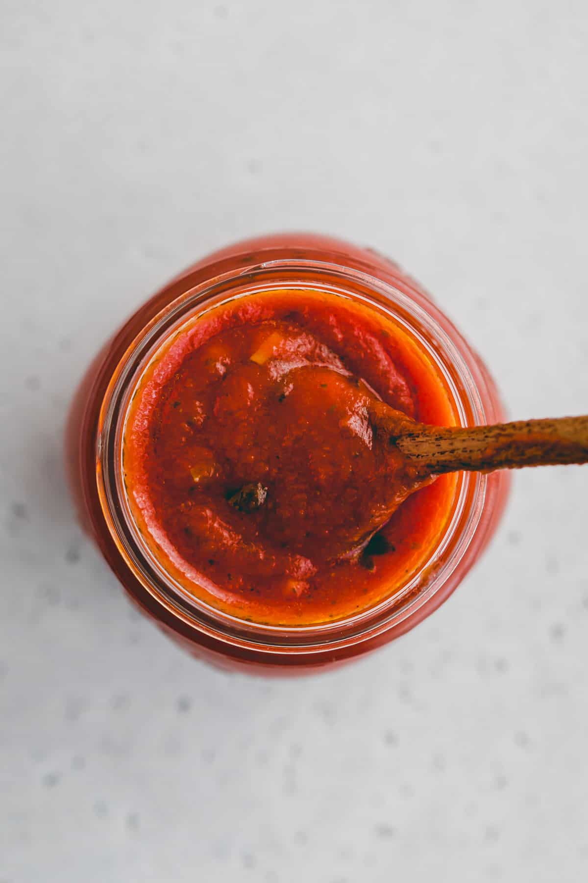 a spoon in a jar of pizza sauce