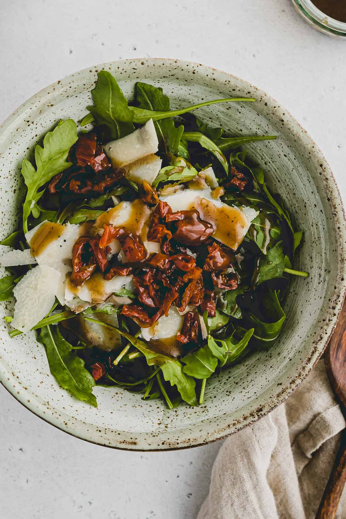 italian arugula salad with shaved parmesan and sun-dried tomatoes in a bowl