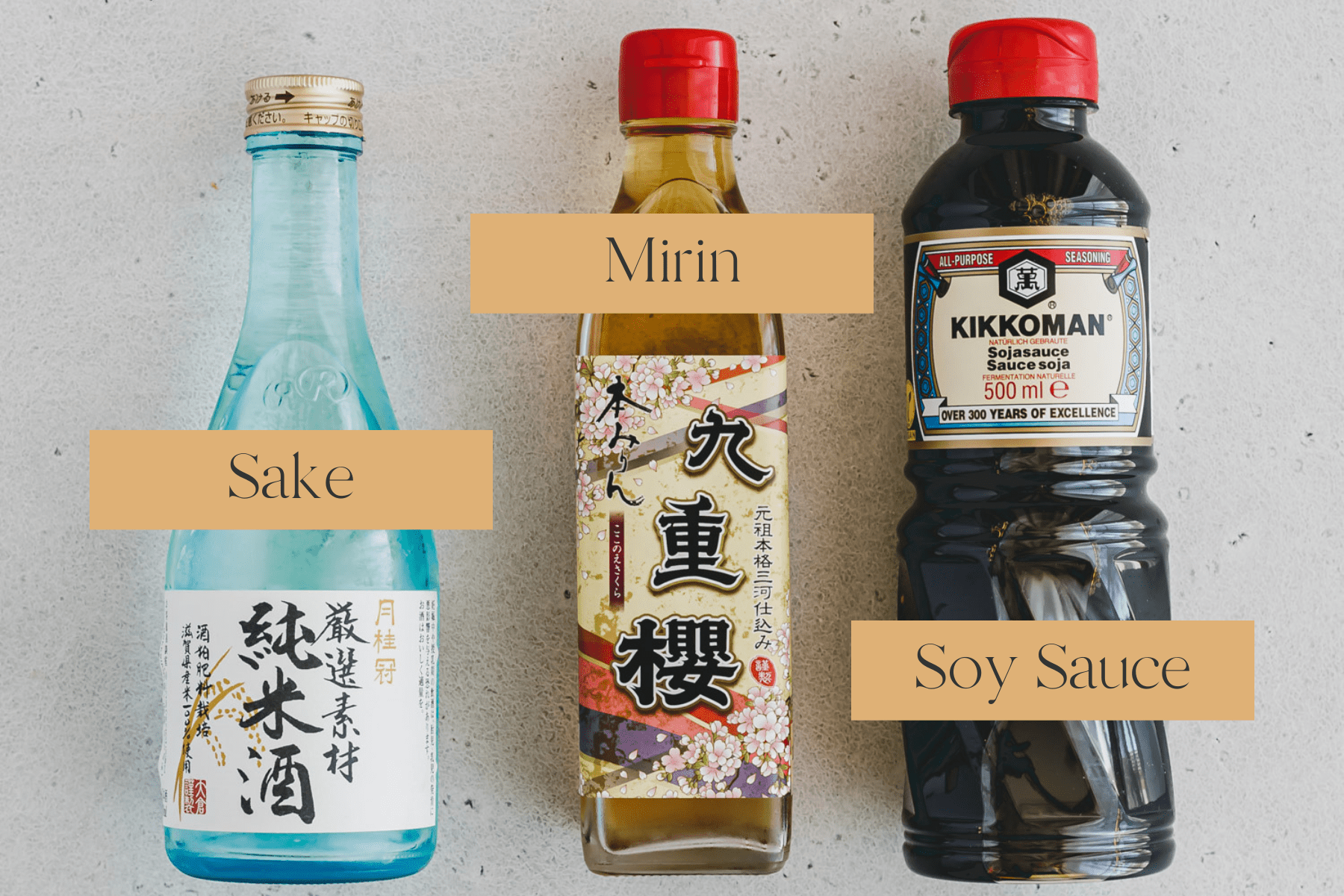 Top view of three bottles lying on a table: sake, mirin and soy sauce. 