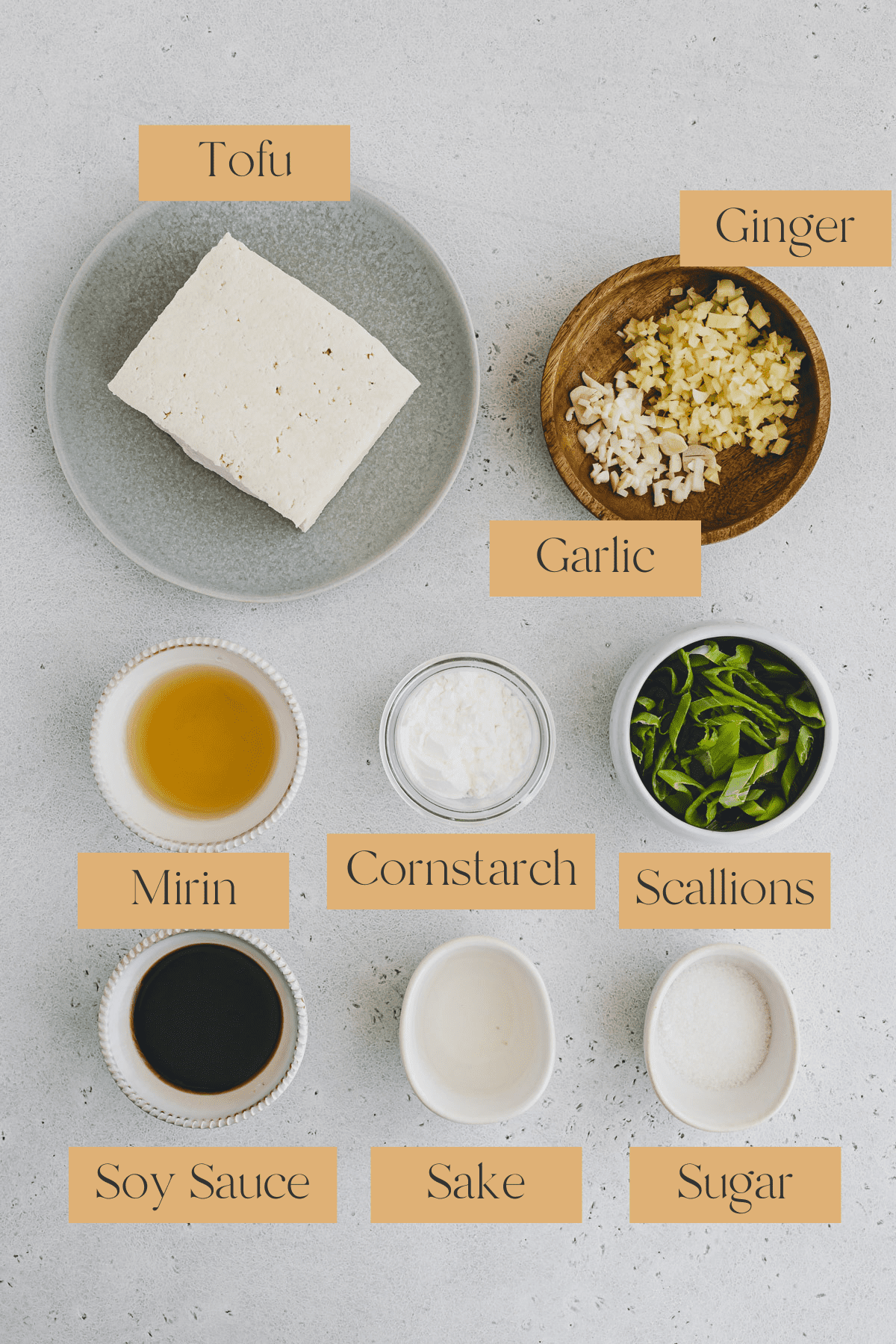 Top view of ingredients in small bowls including tofu, ginger, mirin, cornstarch, scallions, soy sauce, sake and sugar. 