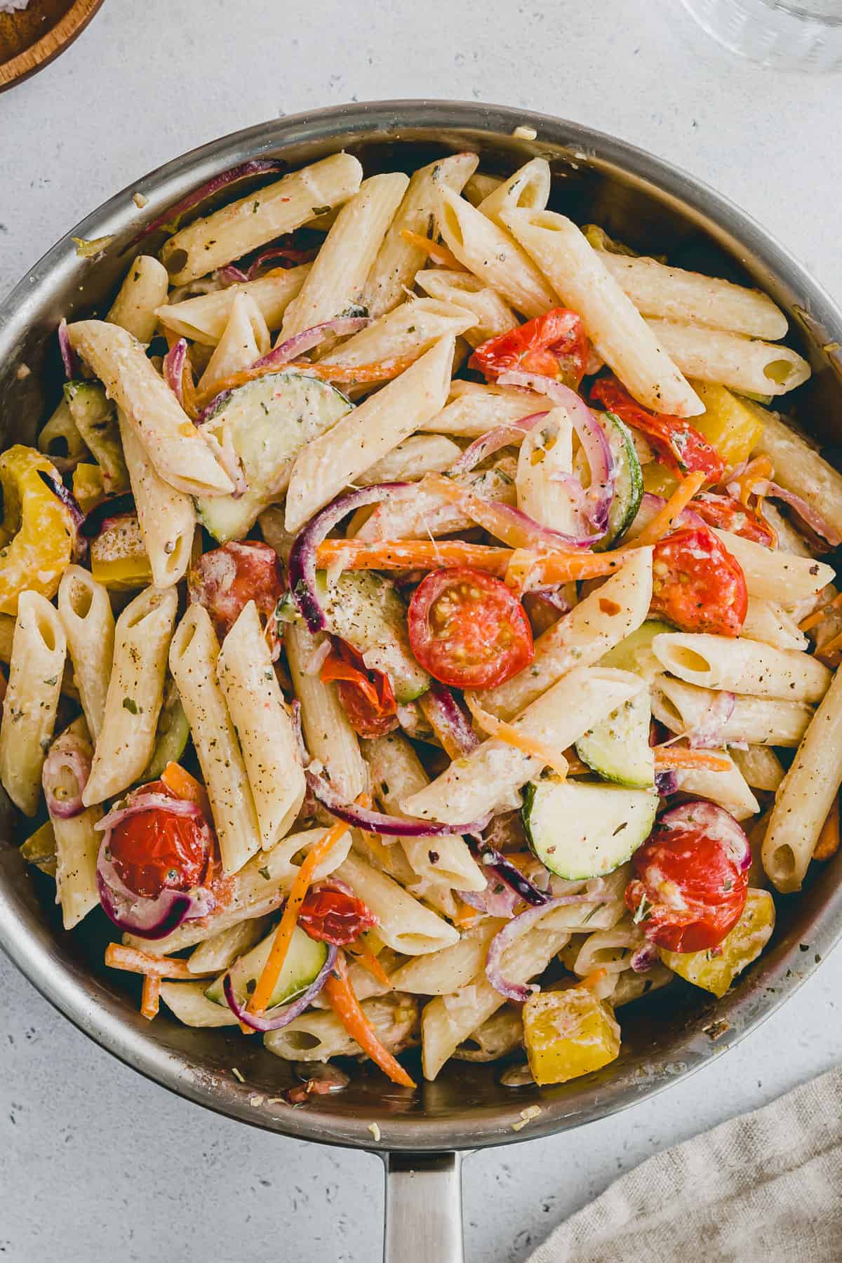 Close up hero shot of a top view of a pan filled with pasta and veggies in a creamy sauce. 