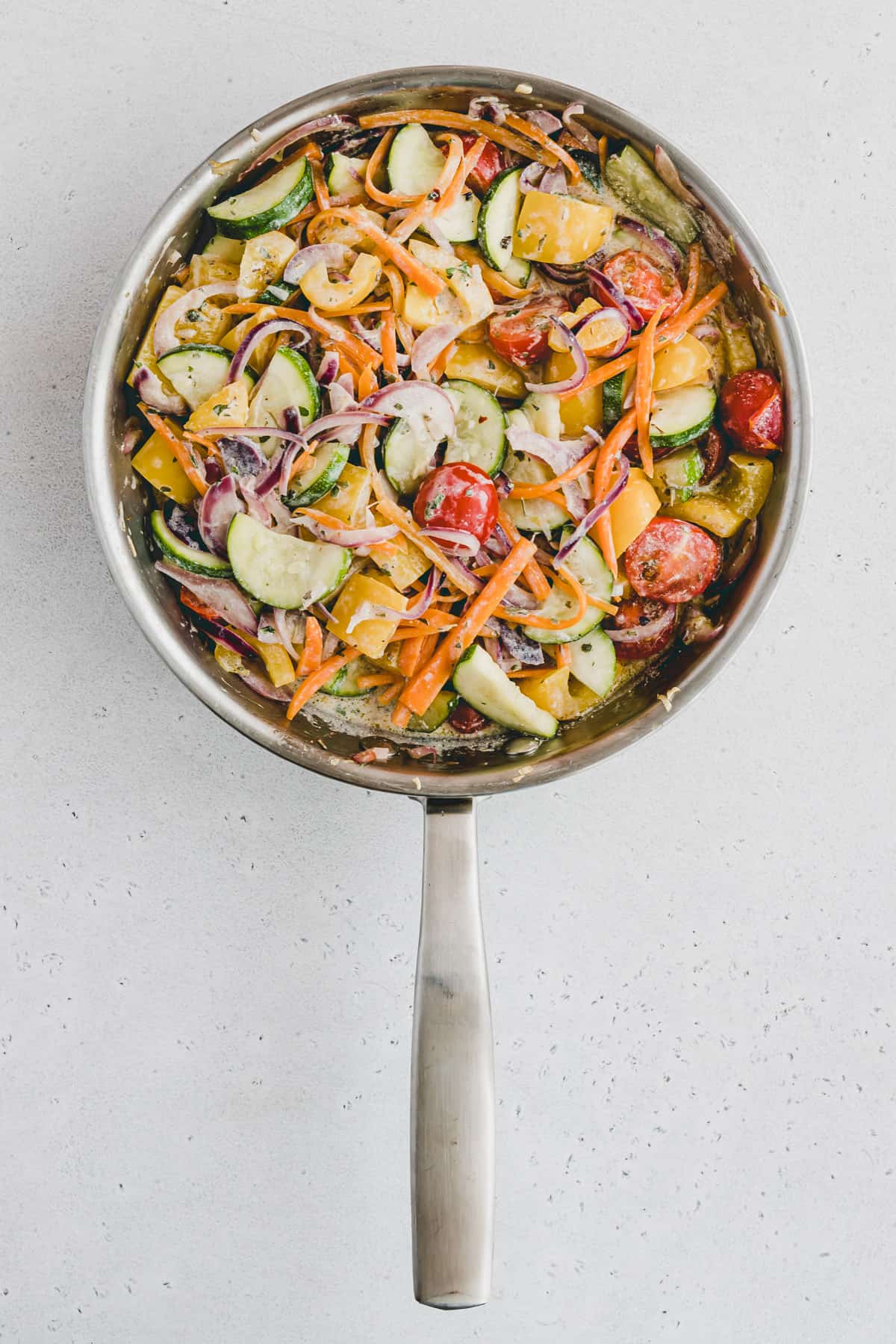 Top view of a pan filled with chopped vegetables in a creamy sauce. 