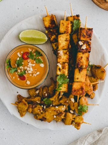 vegan satay skewers on a plate with peanut dipping sauce