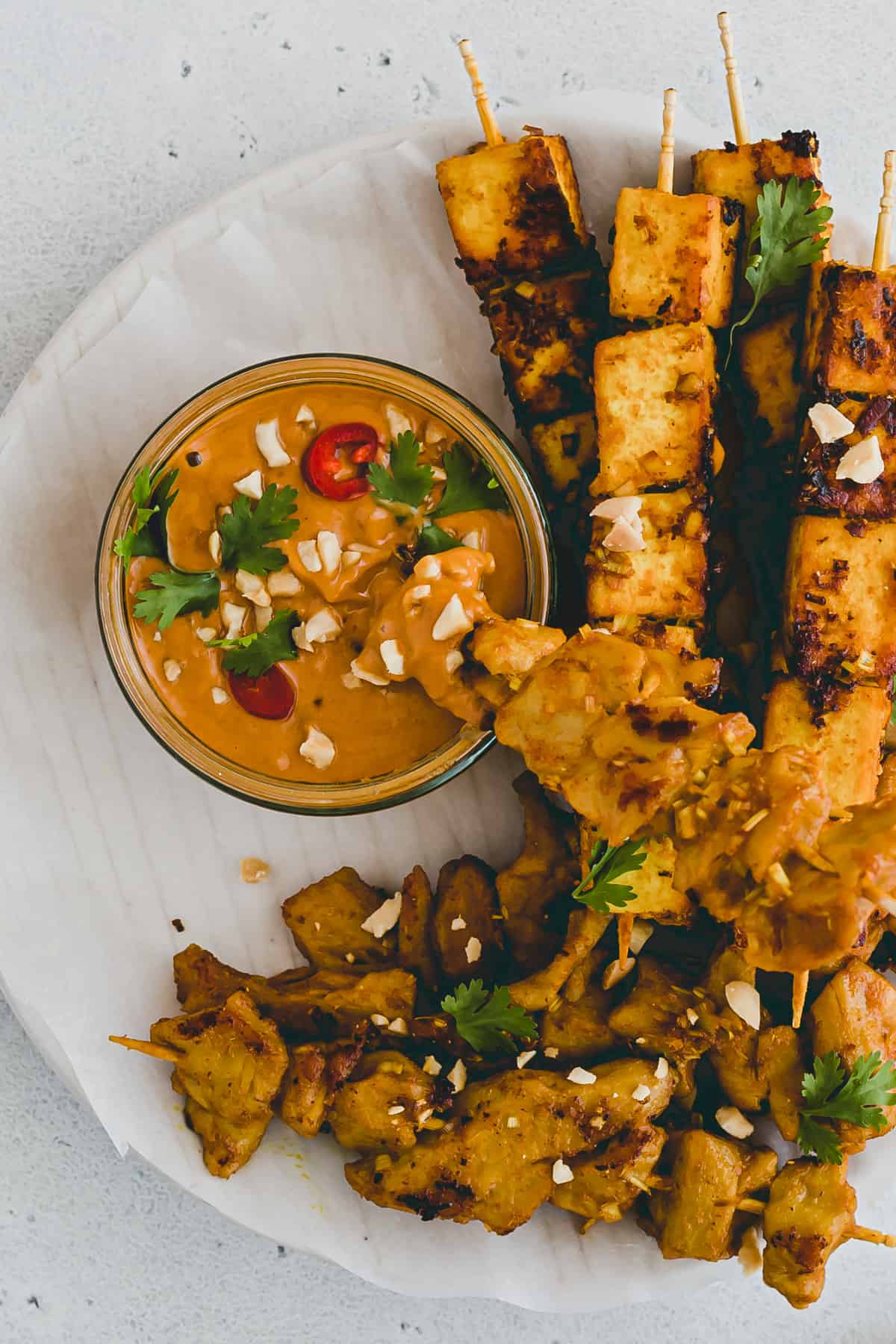 ein satay spiess dippt in satay sauce