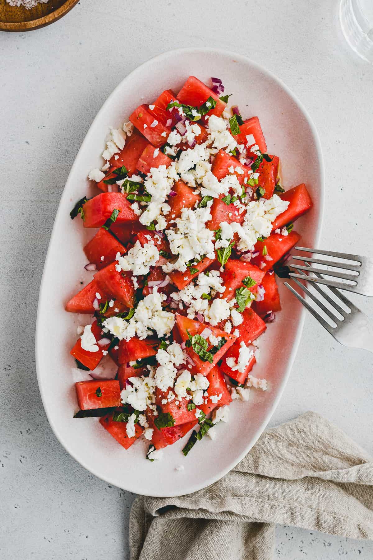two fork on a serving platter with watermelon salad