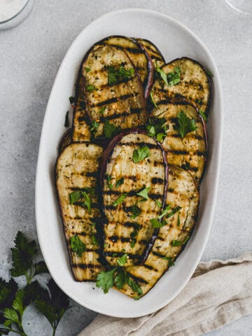 Grilled Eggplant topped with parsley on a serving platter