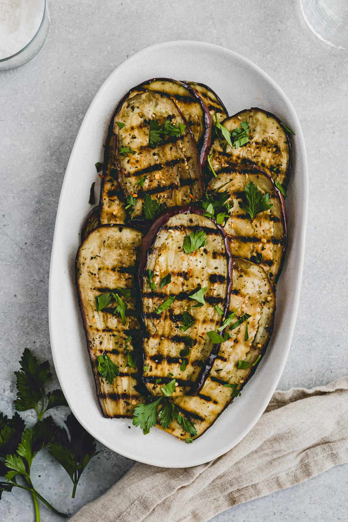 Grilled Eggplant topped with parsley on a serving platter