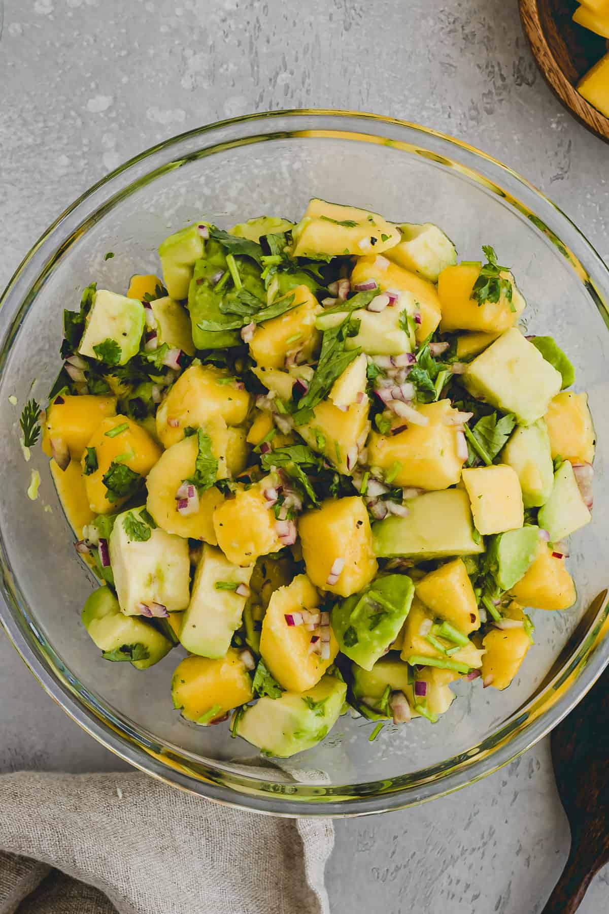 Close up top view of a glass bowl filled with mango avocado salad.