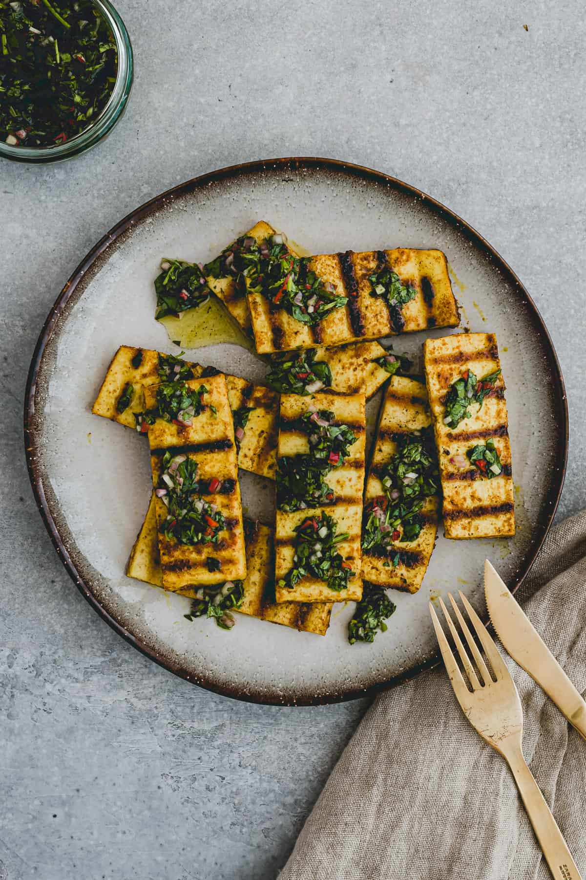 Top view of a plate with grilled tofu steaks topped with chimichurri sauce!