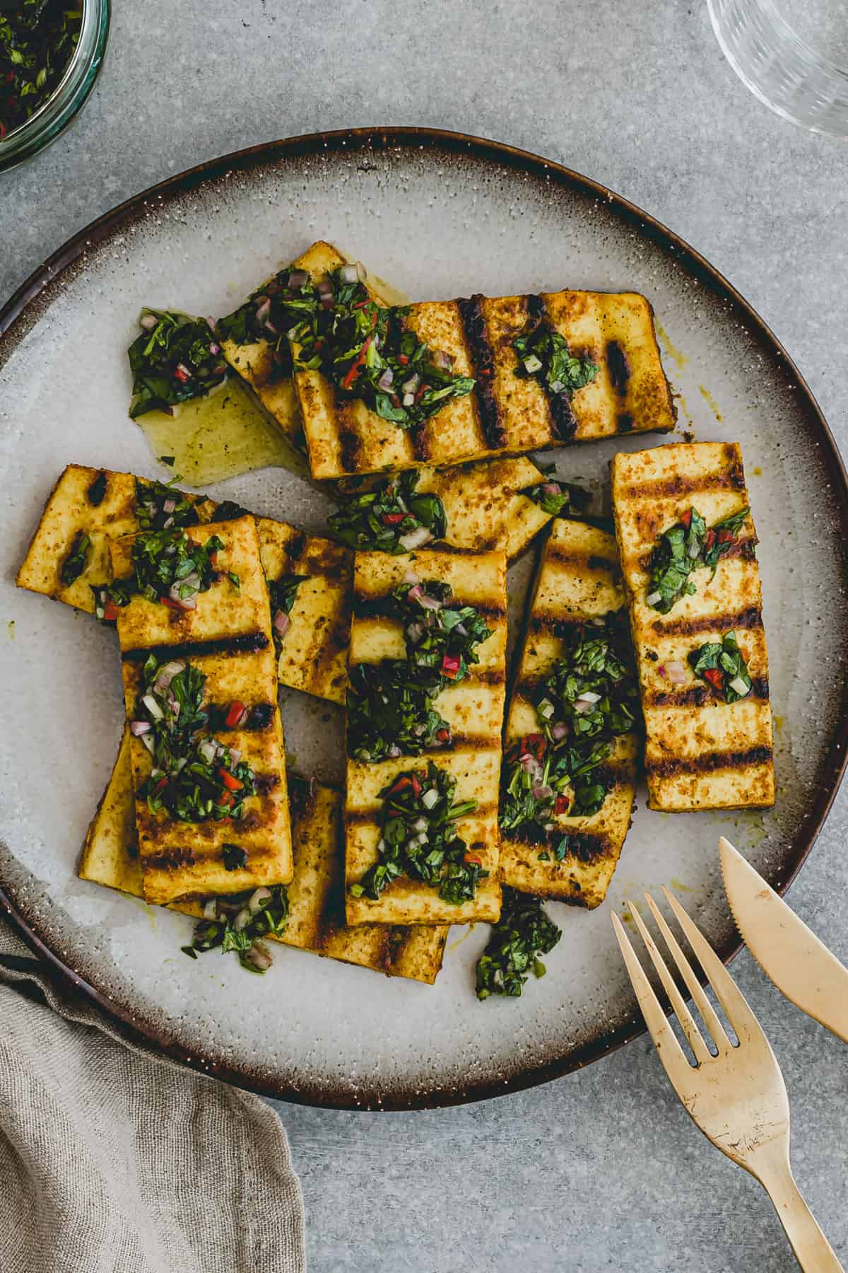 Close-up of a top view of a plate with grilled tofu steaks topped with chimichurri sauce!