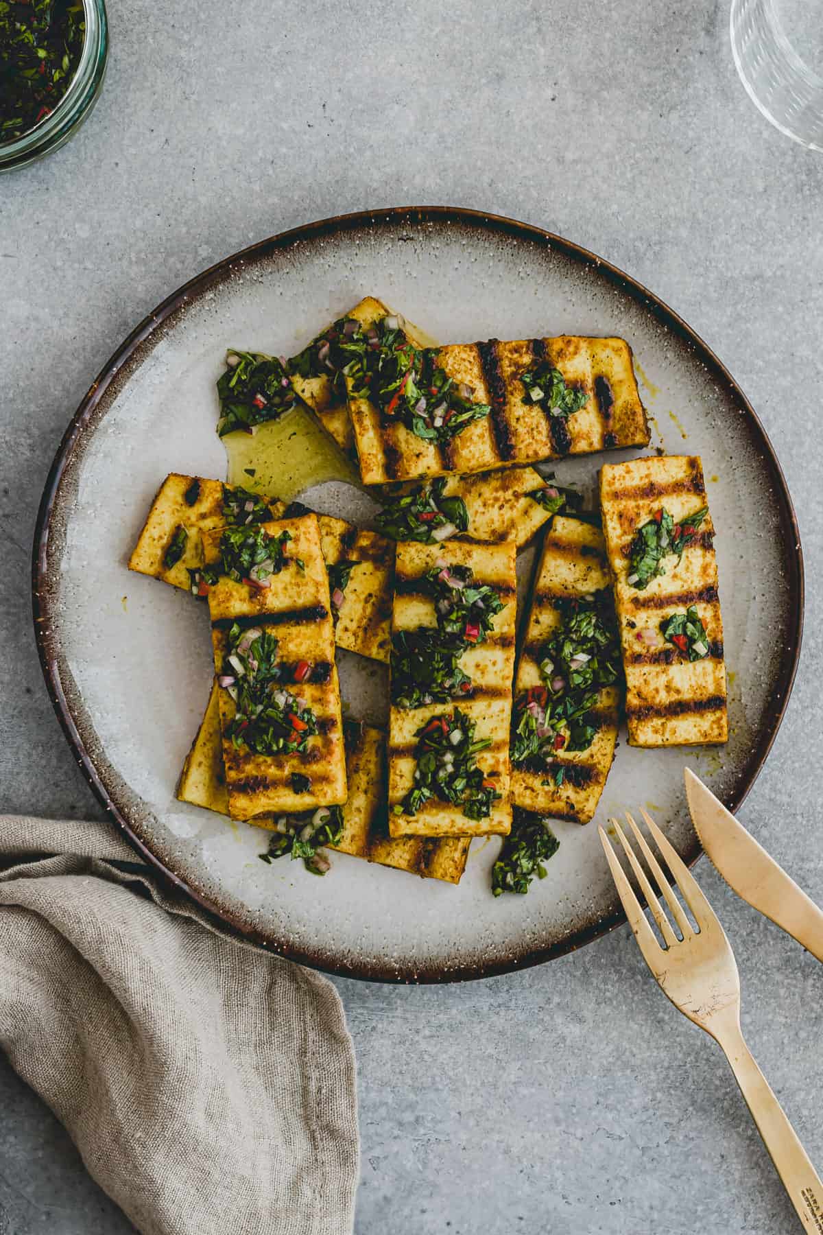 Top view of a plate with grilled tofu steaks topped with a homemade green and red chimichurri sauce!