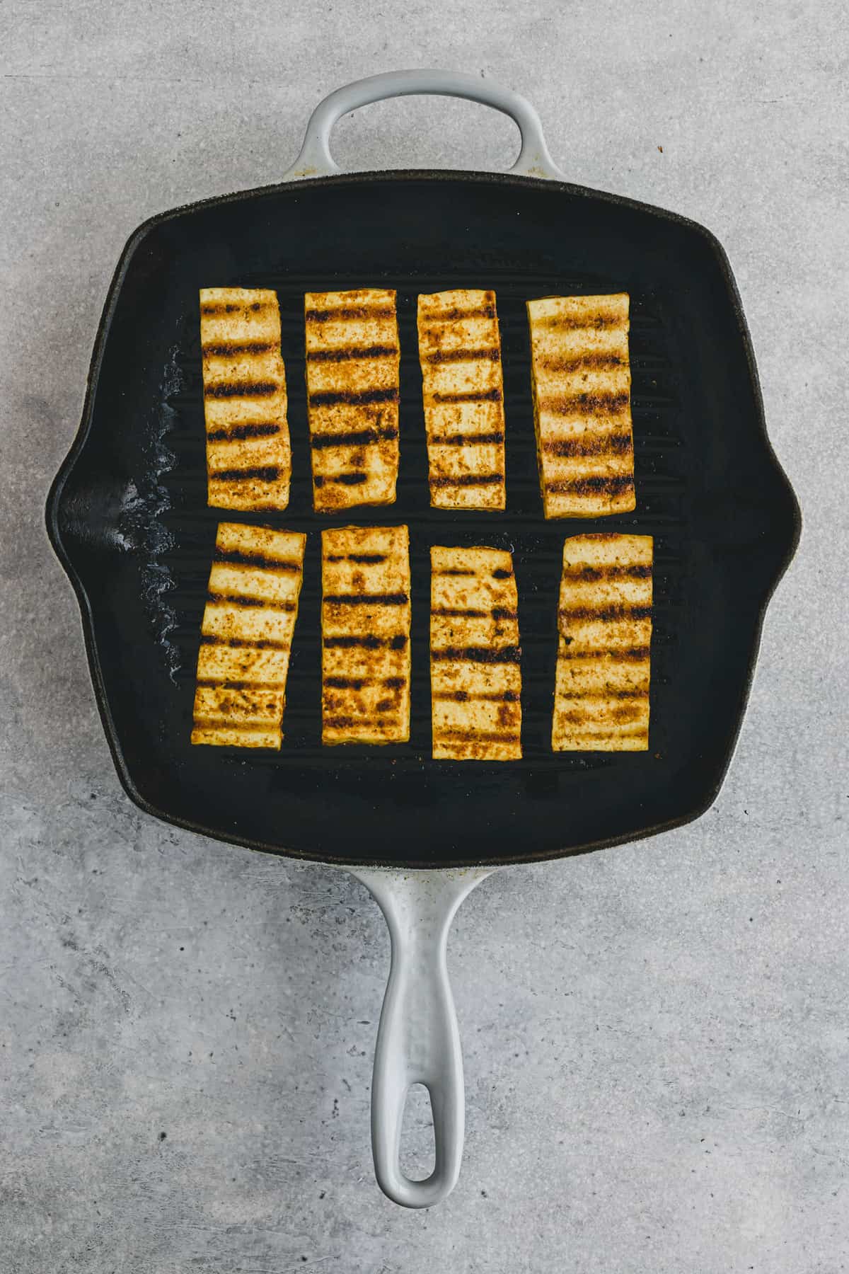 Top view of tofu steaks being grilled in a grill pan. 