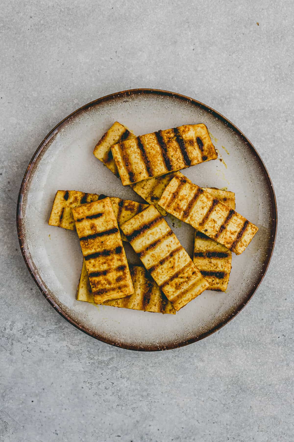 Top view of grilled tofu steaks on a plate. 