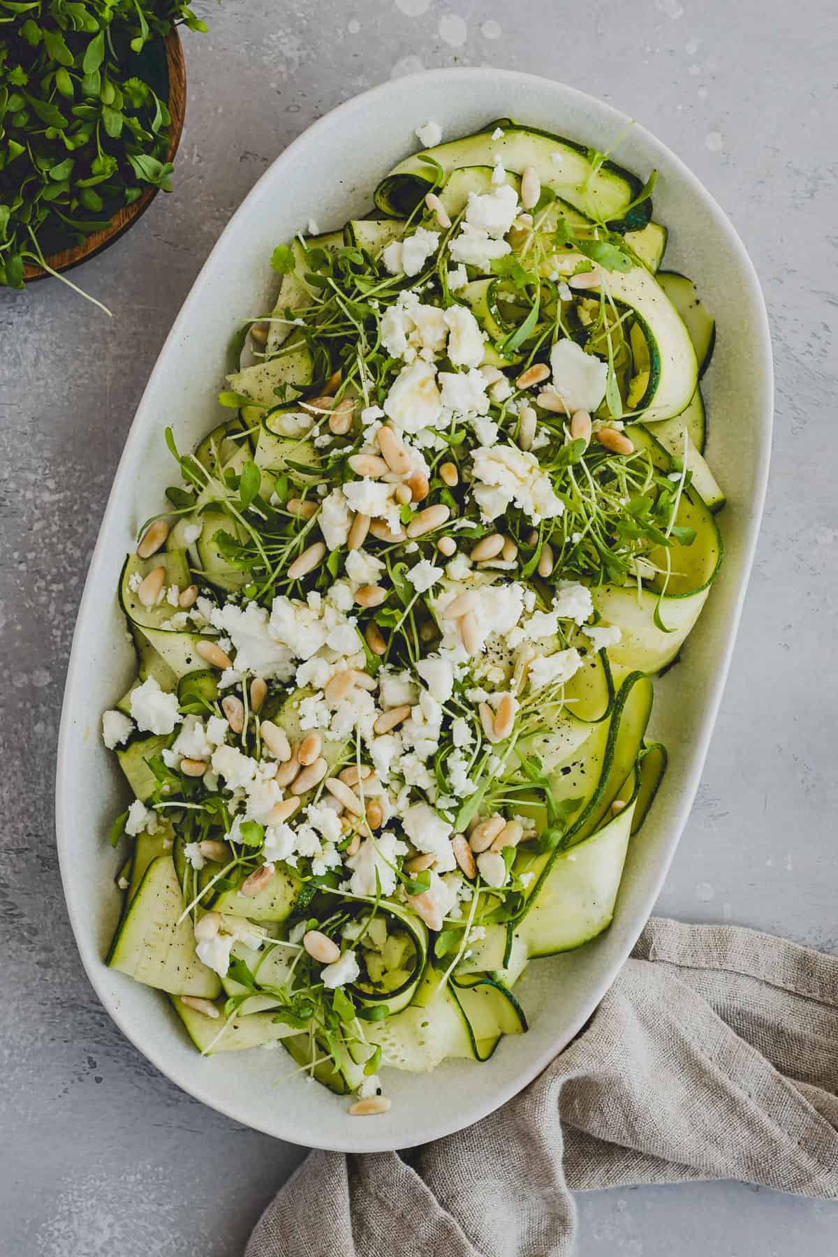 zucchini salad with feta and microgreens on a serving platter