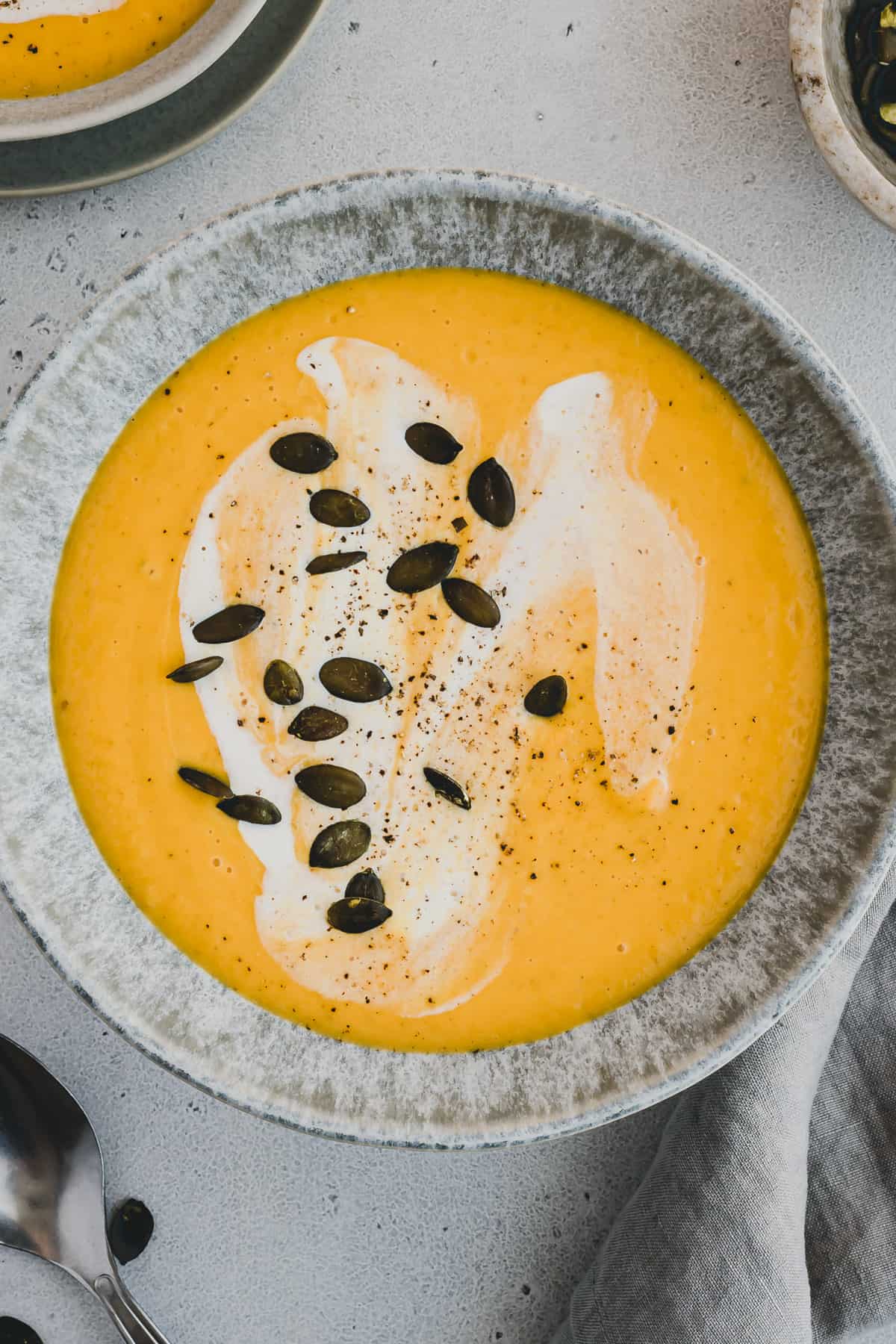 roasted pumpkin apple soup in a bowl decorated with pumpkin seeds