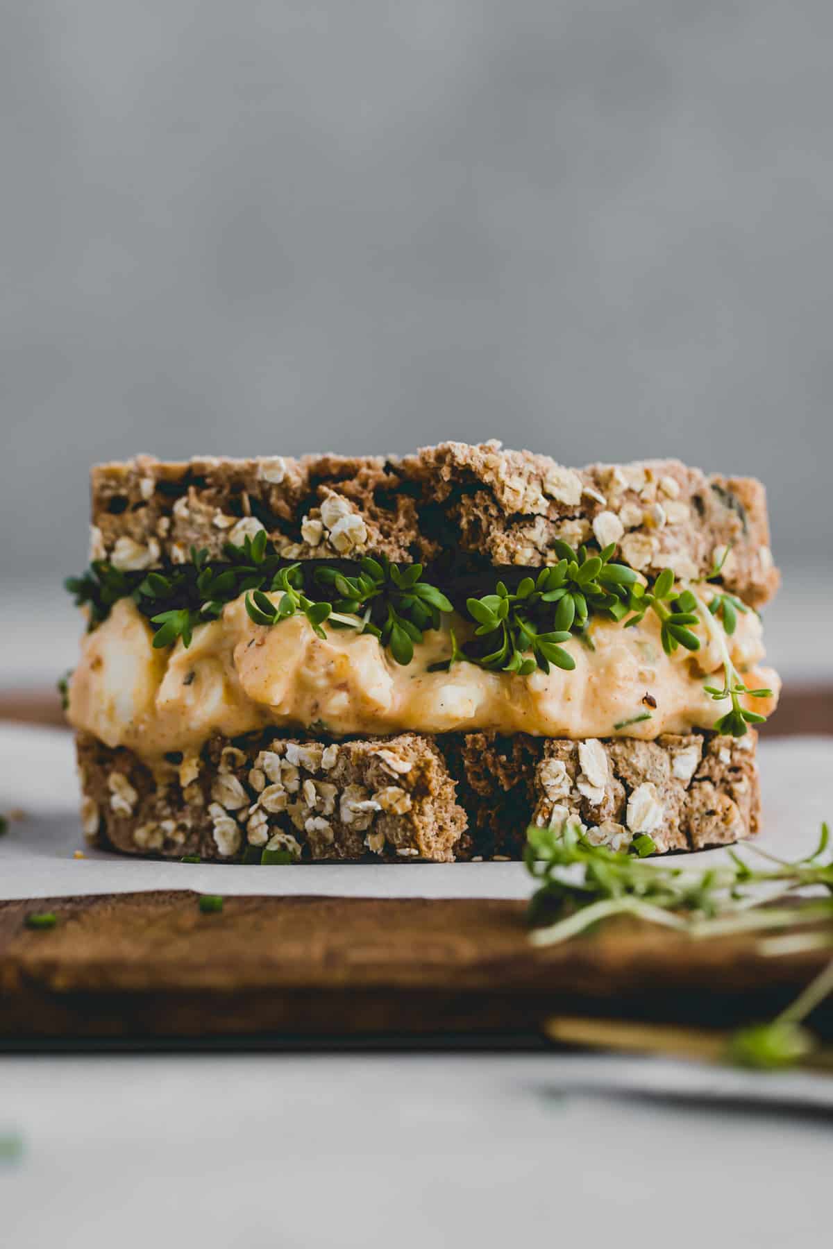 egg salad sandwich with garden cress on a chopping board