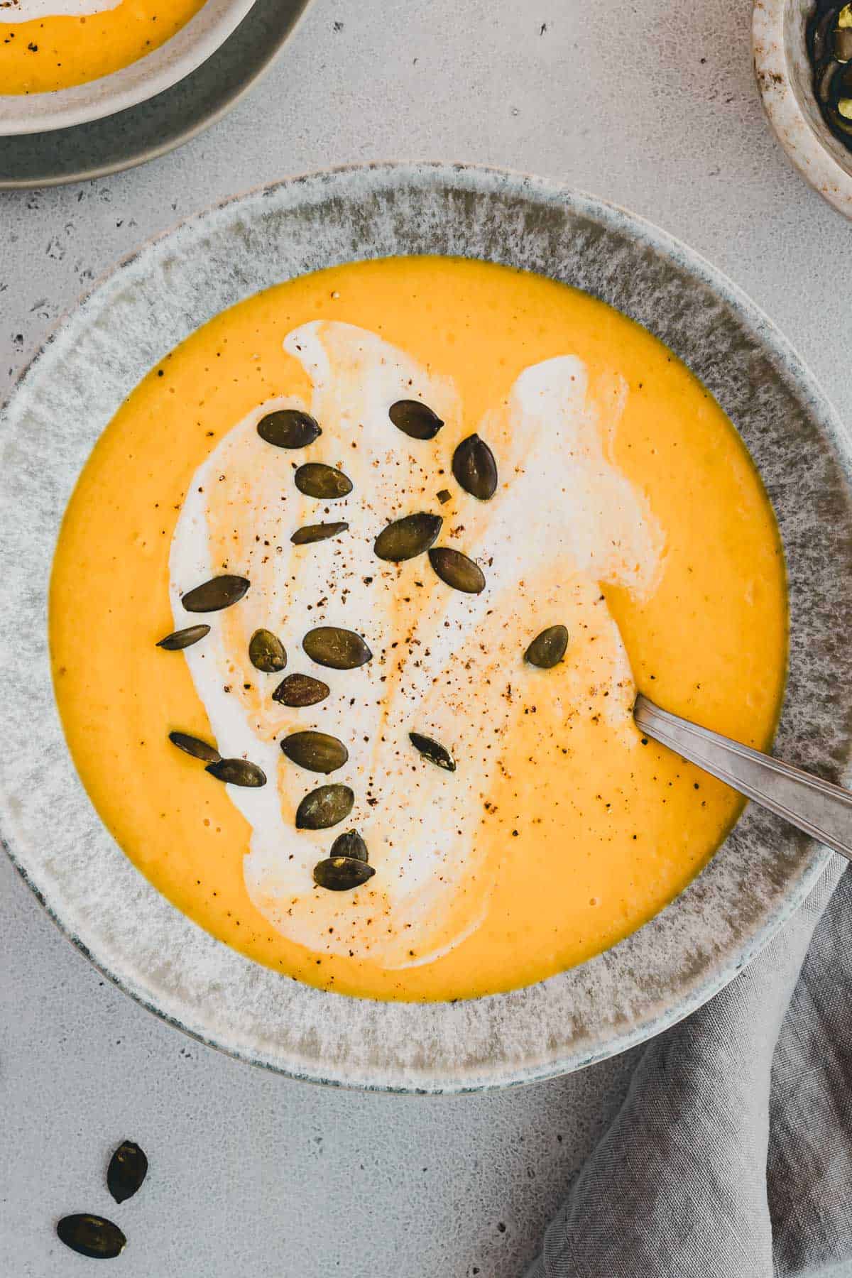 Kürbis Apfel Suppe einer Suppenschüssel mit Kürbiskernen dekoriert und von oben fotografiert