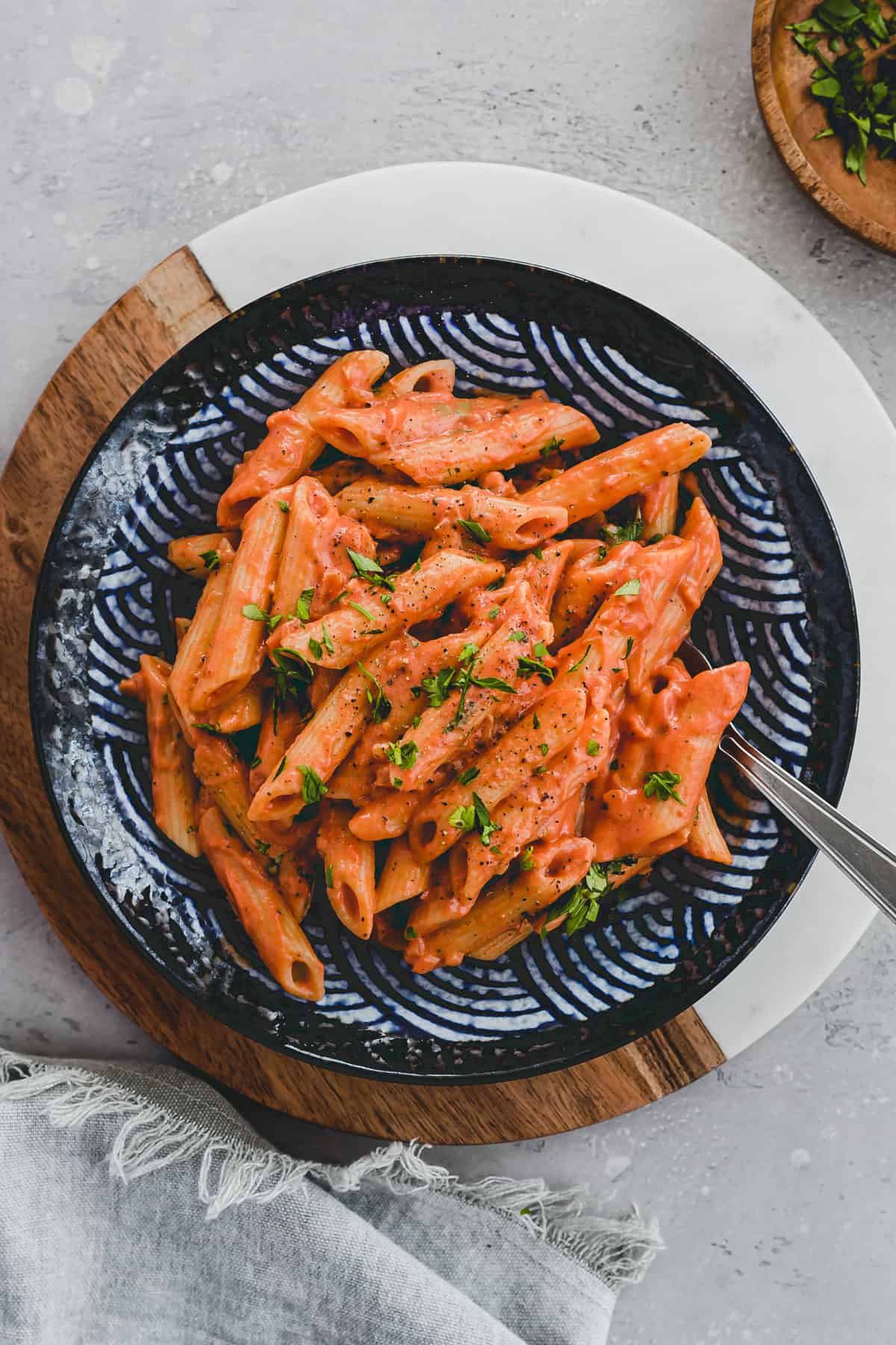 vegan vodka pasta in a blue plate garnished with parsley