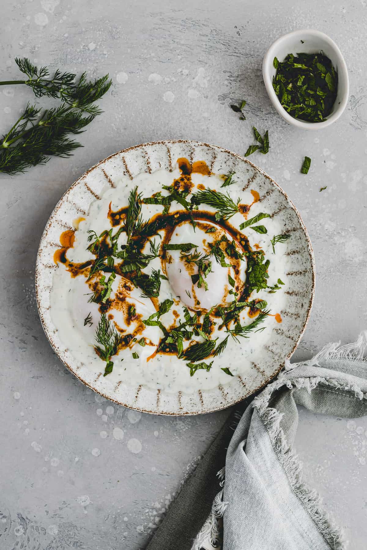 Turkish Eggs served on a plate with fresh herbs