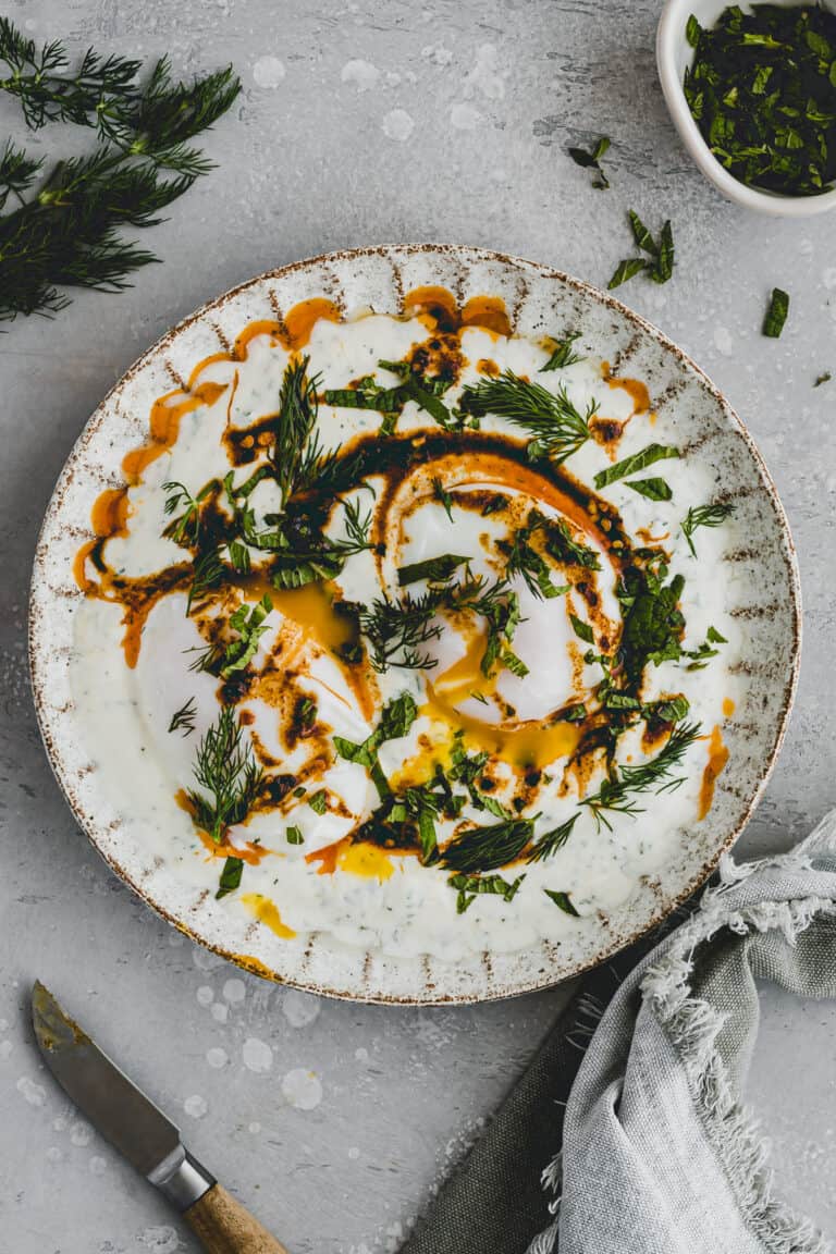 Turkish Eggs served on a plate with fresh herbs