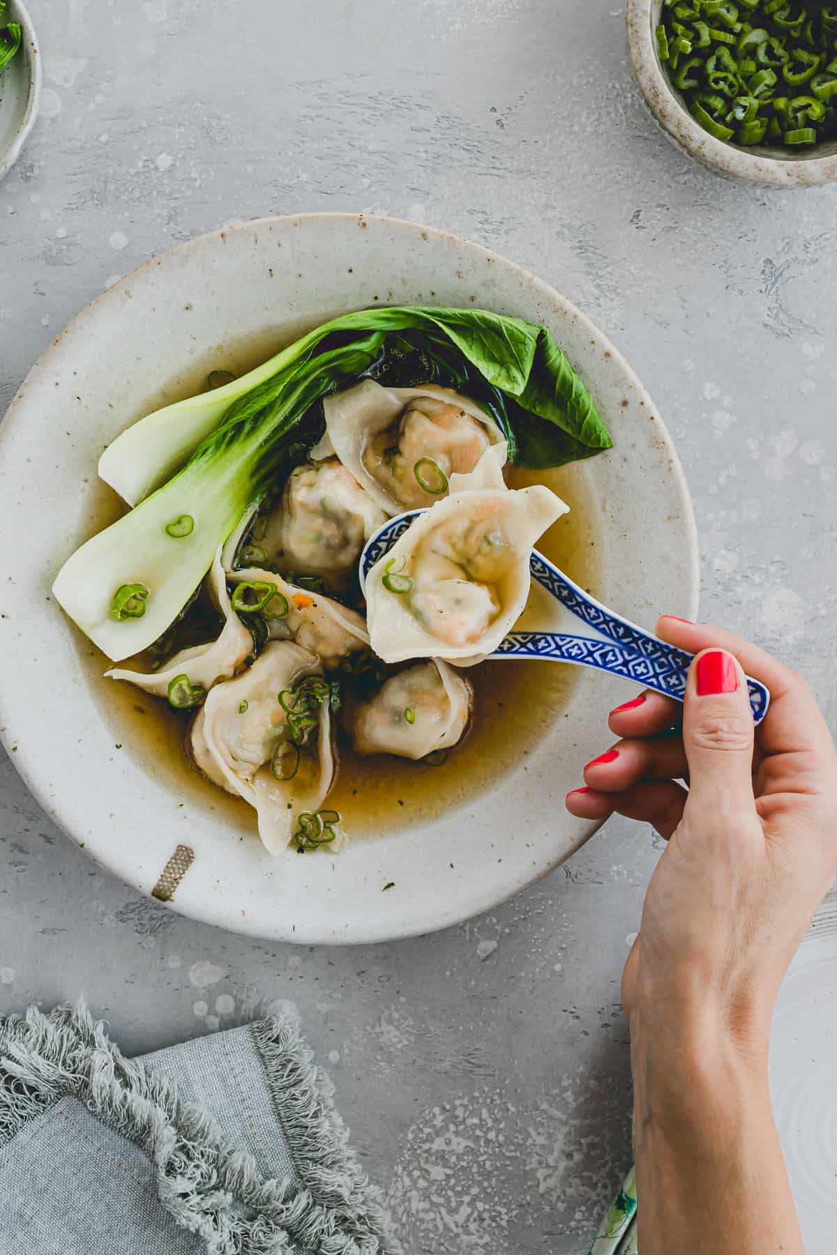 one hand holding a spoon with vegan wonton wrapper