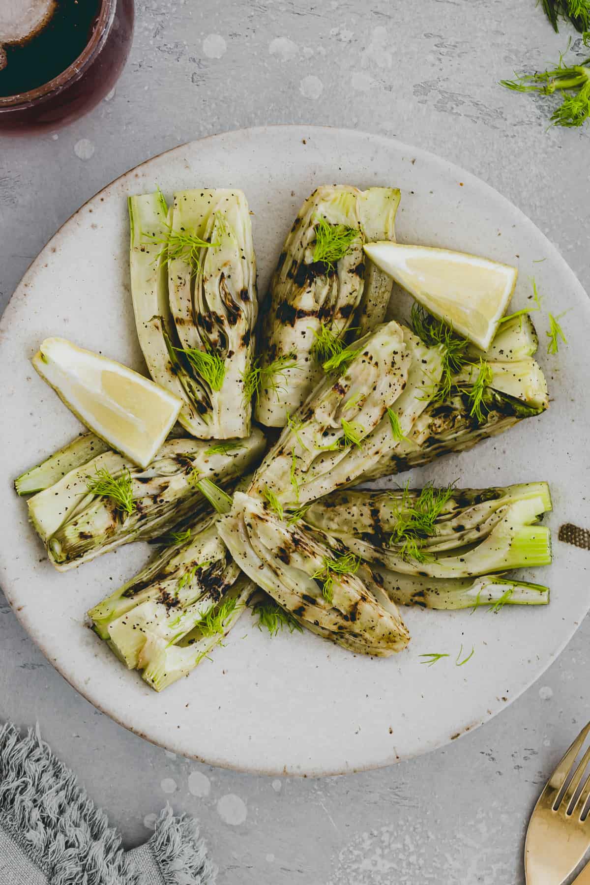 gegrillter fenchel auf einem teller mit zitronenschnitzen